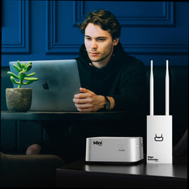 PKTPAL Edge Extender (white unit with two antennas) on a desk beside the Mini unit